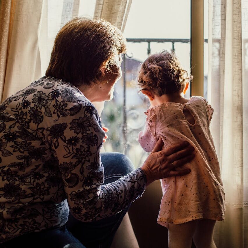 Grandmother looking out window with grandchild